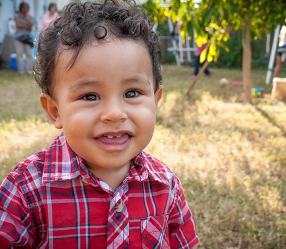 Little boy in plaid shirt outside with two front teeth