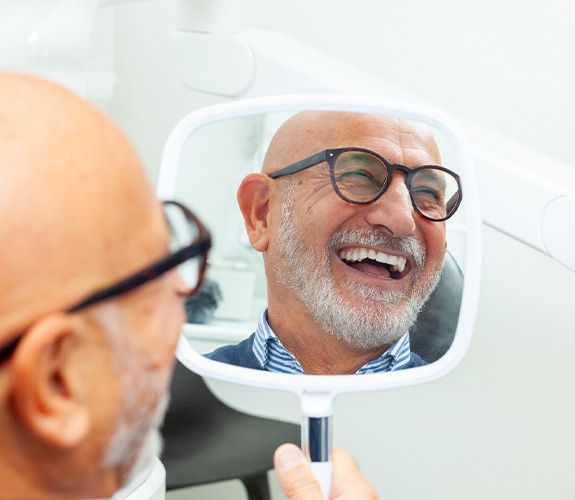Older man pleased with his new smile and learning about dental implant post-op instructions in Lockport