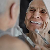 Man holding a toothbrush and smiling in the mirror
