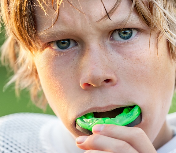 Teen boy placing green athletic mouthguard