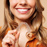Woman holding a clear aligner in her hand