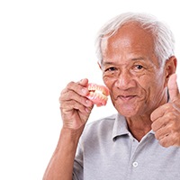 Man with missing teeth holding dentures