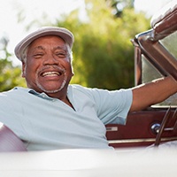 Older man driving vehicle and smiling
