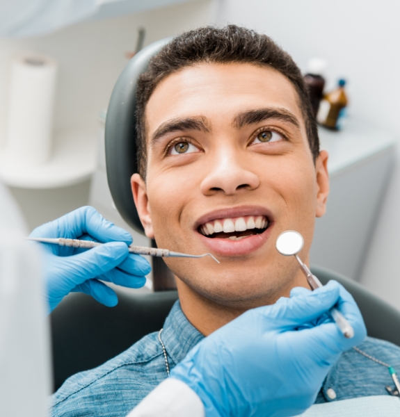 Patient in dental chair smiling at dentist