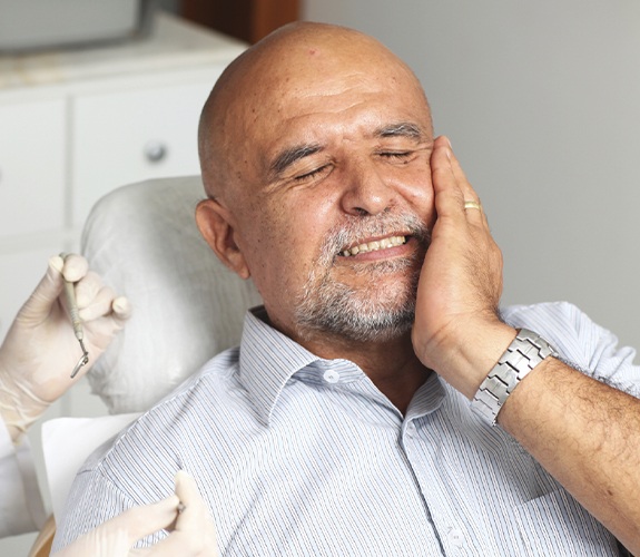 Man in need of emergency dentistry holding jaw in pain
