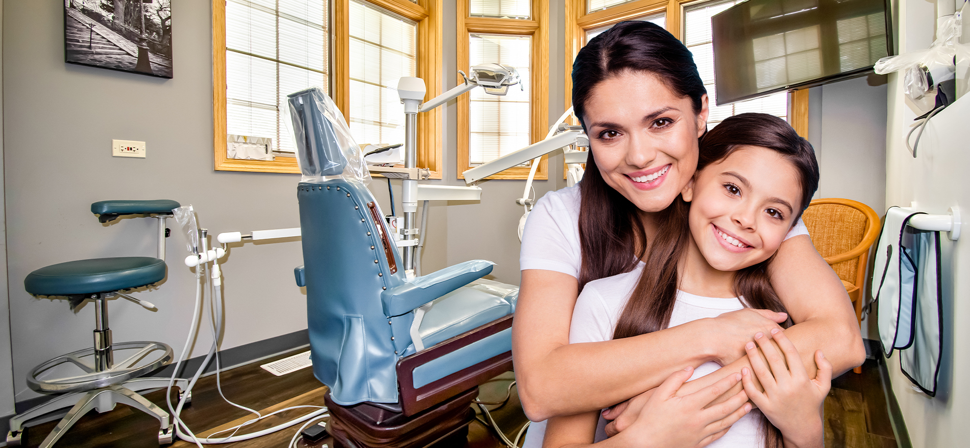 Smiling mother and daughter in dental office treatment room