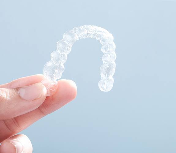 Close up on a person holding an Invisalign clear aligner