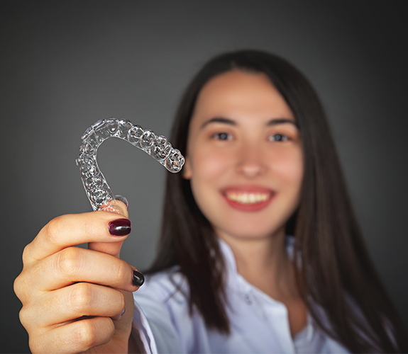 Woman holding up an Invisalign tray