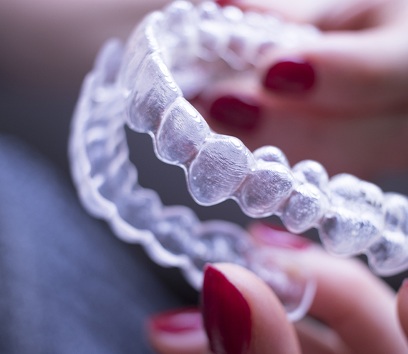 Hand holding an individual Invisalign clear braces tray