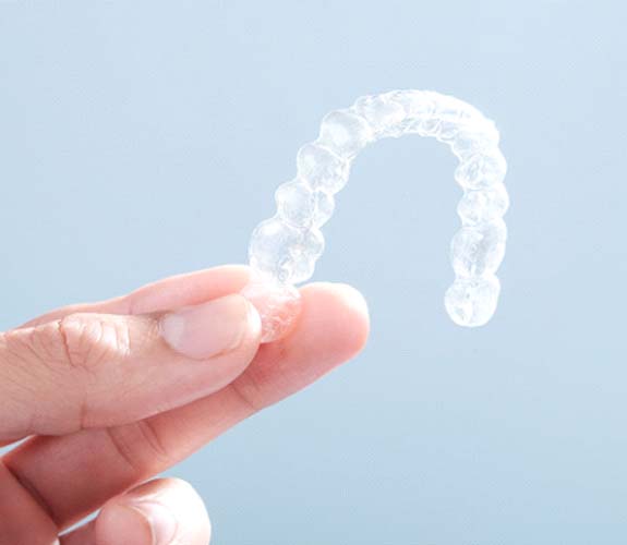 Close-up of hand holding a clear aligner for Invisalign Teen in Lockport, IL