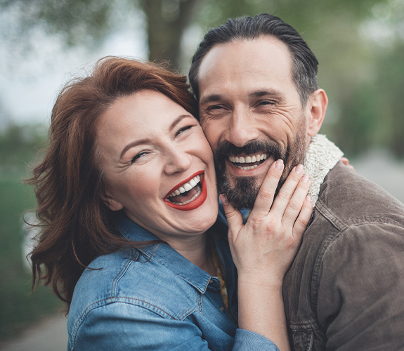 Man and woman smiling after dental implant tooth replacement