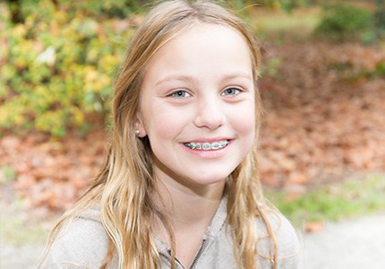 Young woman with traditional orthodontics smiling