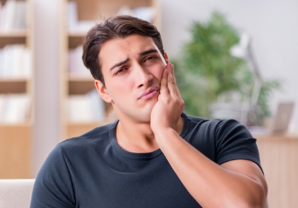 Man in need of emergency dentistry holding cheek