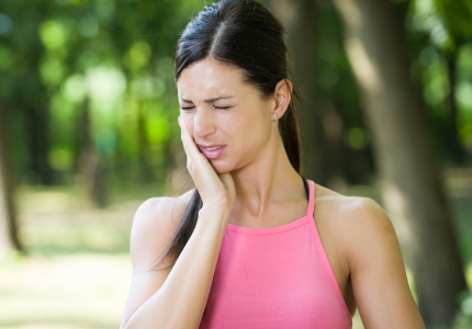 Woman in need of restorative dentistry holding cheek