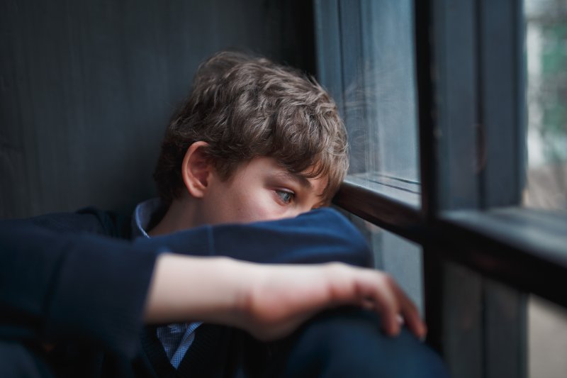 Sad boy sitting by a windowsill