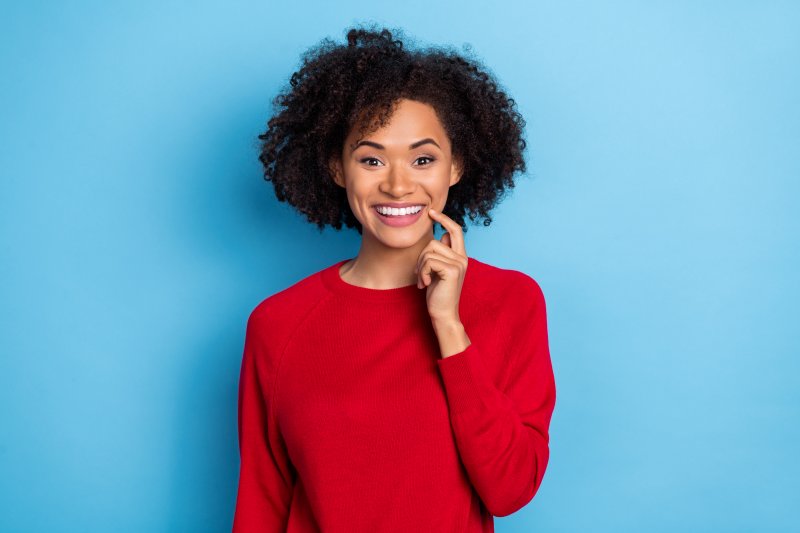 woman in red sweater showing off cosmetic dentistry results