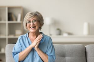 An older woman wearing glasses and smiling with dental implants
